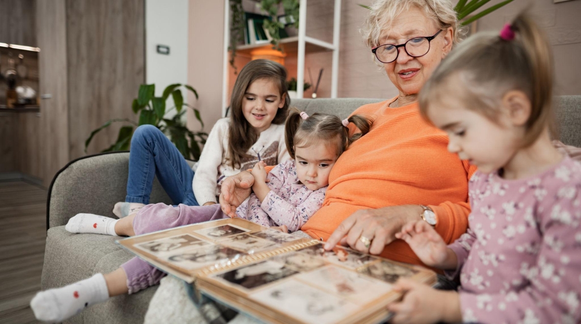 Babcia opowiada wnuczkom historie rodziny pokazując album zdjęć